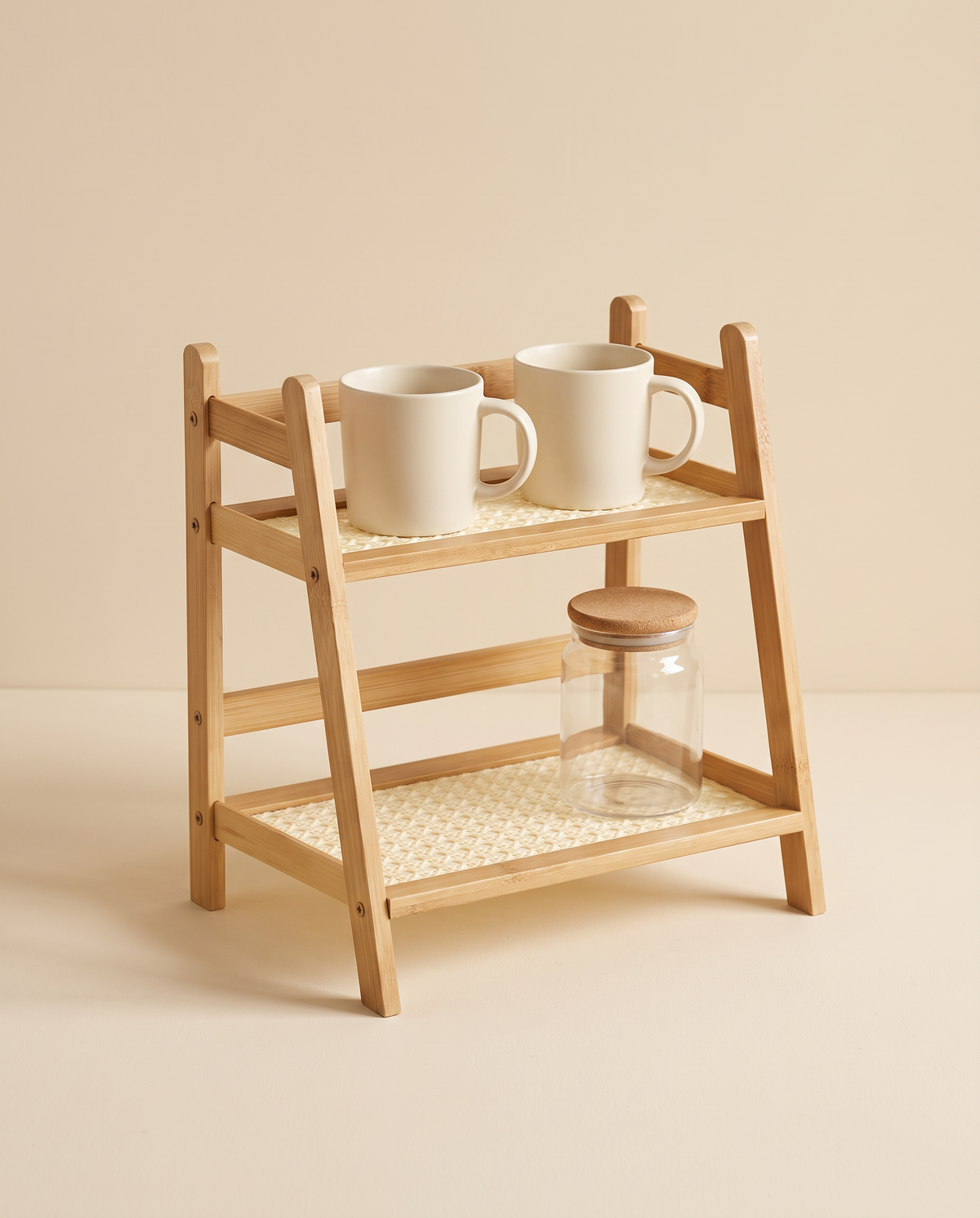 Bamboo two-tier shelf holding mugs and a glass jar