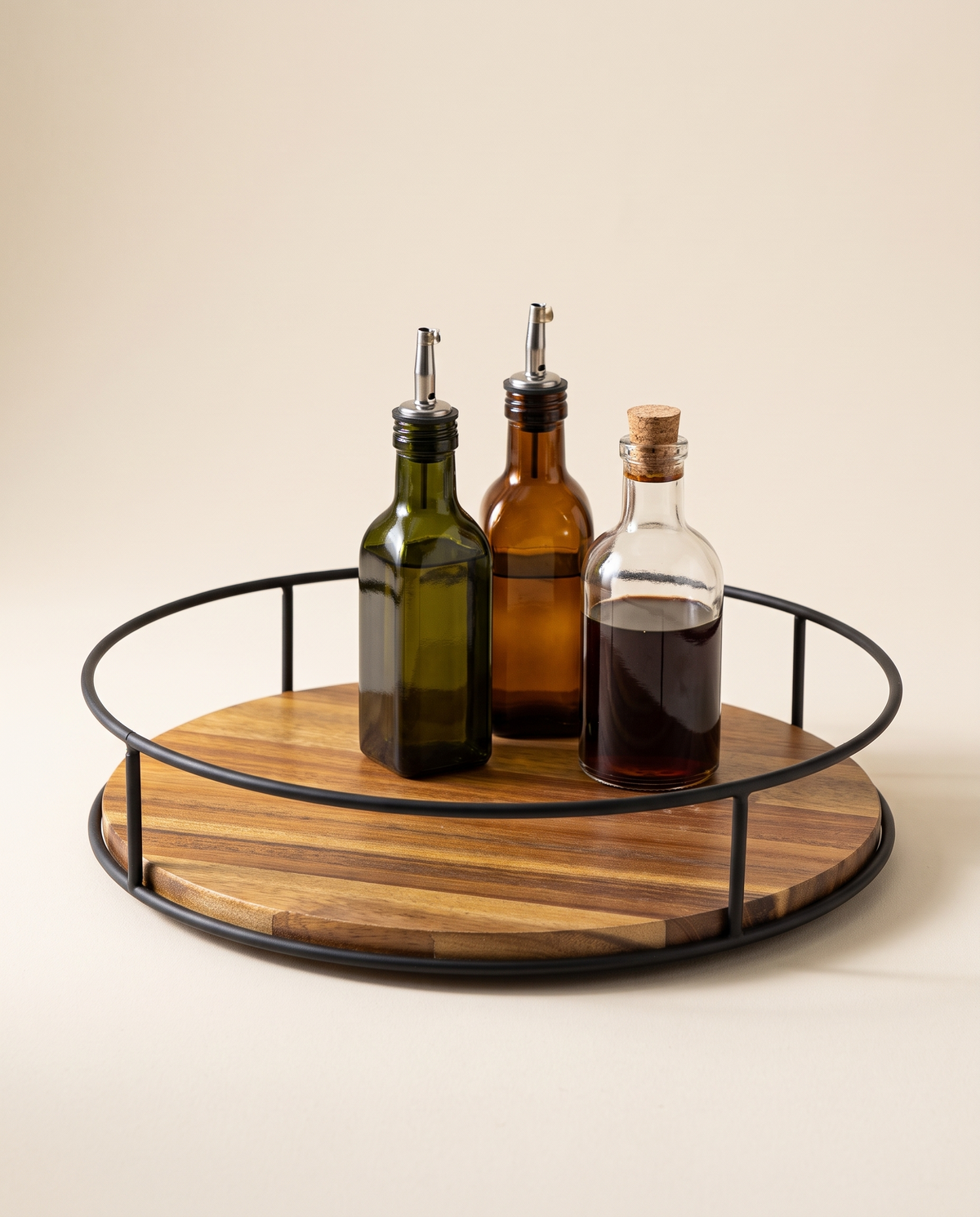 Acacia wood lazy susan with black metal rail holding oil and vinegar bottles